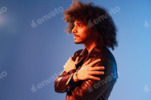 Preview: Portrait of a stylish man with curly hair on a blue background multinational, colored light, black