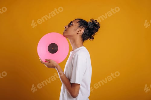 Preview: Pink colored vinyl record, music lover. Young guy is against yellow background