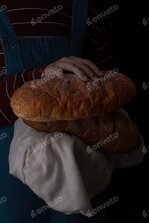 Preview: Woman in a striped shirt grasps two loaves of bread.