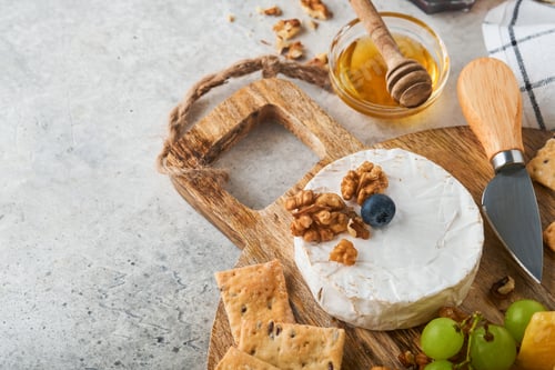 Preview: Assortment of cheese, honey, cracker, blueberries, grapes with red and white wine in glasses antipas