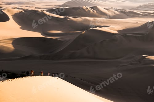 Preview: People climbing sand dunes to watch the sunset over the desert at Huacachina, Ica Region, Peru, Sout