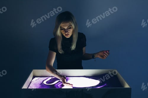 Preview: Sand Animation. A Young Beautiful Blonde Woman Paints On An Interactive Sand Table.