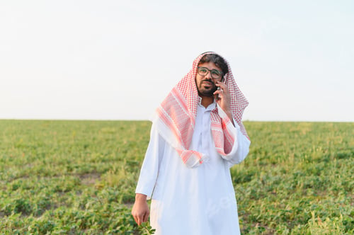 Preview: Arab farmer using mobile phone in soybean field