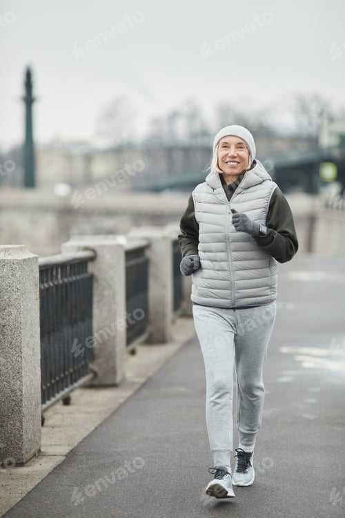 Preview: Cheerful senior woman brisk walking in winter