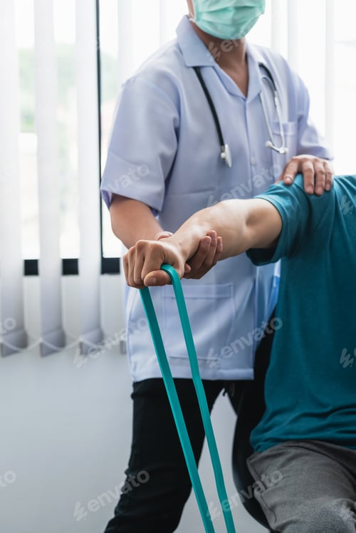 Preview: A physiotherapist is helping a patient stretch his arm using cloth at the clinic.