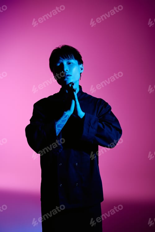 Preview: Handsome stylish young man poses with hands clasped in front of vibrant colored background
