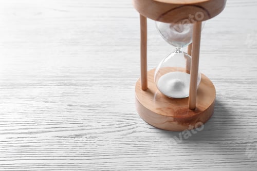 Preview: Hourglass with flowing sand on light wooden background. Time management