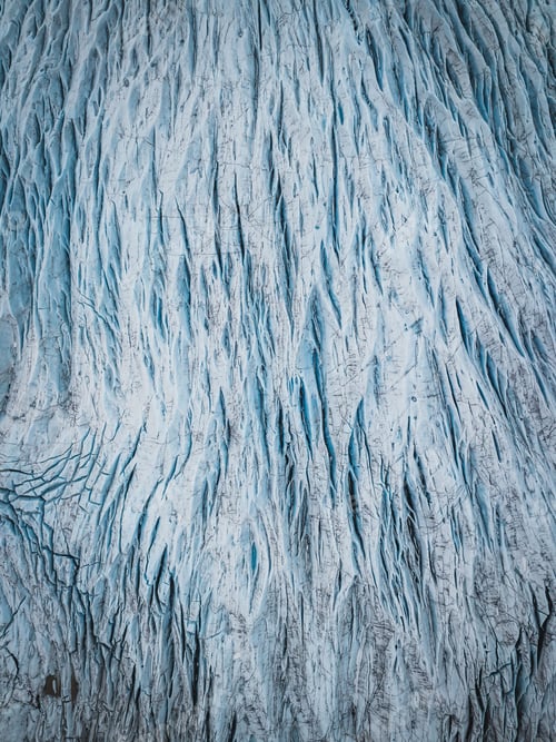 Preview: Aerial view of glacier with intricate crevices and blue ice patterns.