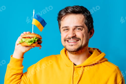 Preview: white guy in yellow hoodie with hamburger and Ukrainian flag on blue background
