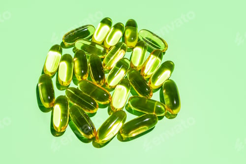 Preview: Golden gelatin capsules folded in a circle, natural omega fatty acid oil on a green background.