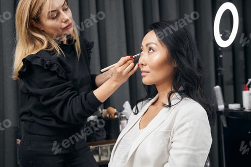 Preview: Beautiful visagiste working with attractive female client in beauty center