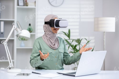 Preview: Woman experiencing virtual reality with VR headset at home office desk working remotely