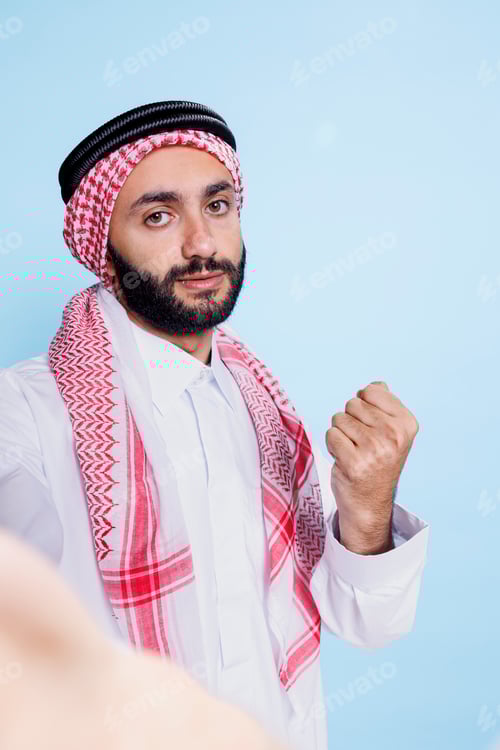 Preview: Arab showing clenched fist at smartphone