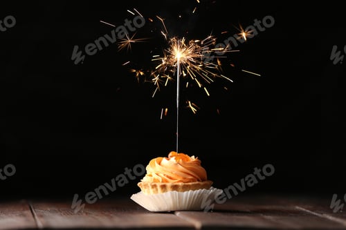 Preview: Delicious dessert with burning sparkler on wooden table against dark background