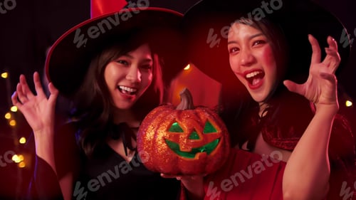Preview: Two young women in witch costumes having fun at Halloween party.