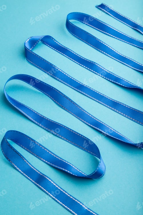 Preview: Blue ribbon on a blue pastel background. Side view.
