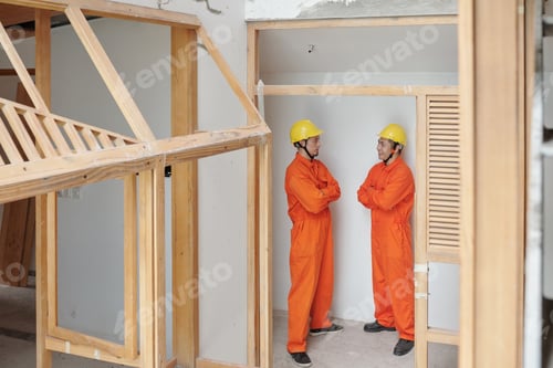 Preview: Positive confident construction workers standing inside building under construction and discussing