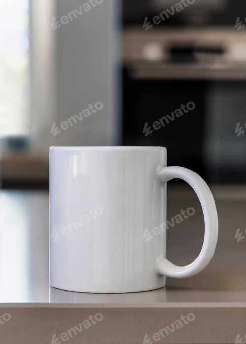 Preview: Closeup of white blank coffee mug on grey kitchen table over blured kitchen interior, mockup