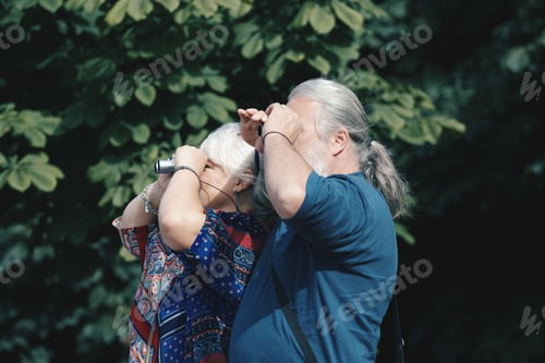 Preview: elderly couple. Senior couple. a man and a woman look through binoculars in the same directions