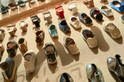 Preview: Assortment of various styles of shoes displayed on a beige background.