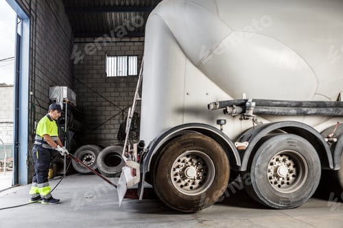 Preview: Serious male mechanic using hydraulic jack to lift truck in garage