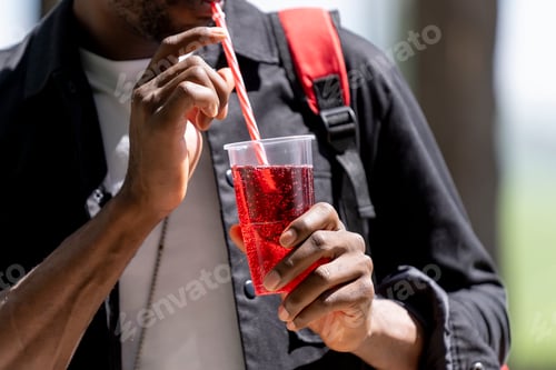 Preview: Close up view of a man with black skin drinking a soft drink through a straw