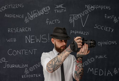 Preview: Bearded dslr photographer with tattooes on his arms.