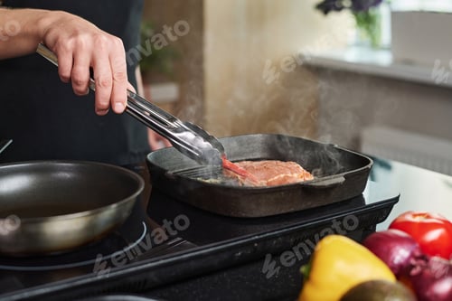 Preview: Man Putting Chili Pepper Next to Frying Steak