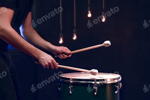 Preview: The drummer plays with mallets on floor tom in dark room.