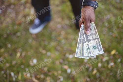 Preview: Overhead closeup shot of a male holding twenty dollar bills wit ha blurred background