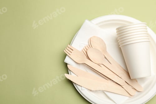 Preview: Set of disposable tableware on olive background, top view. Space for text