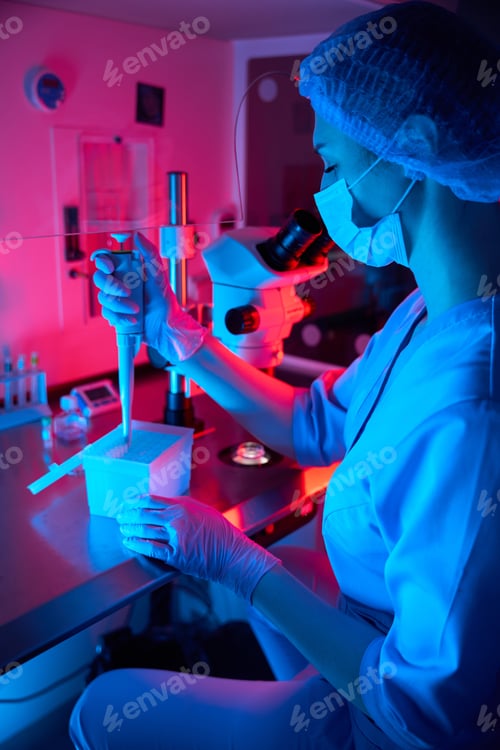 Preview: Female embryologist pipetting samples under dramatic colored lighting