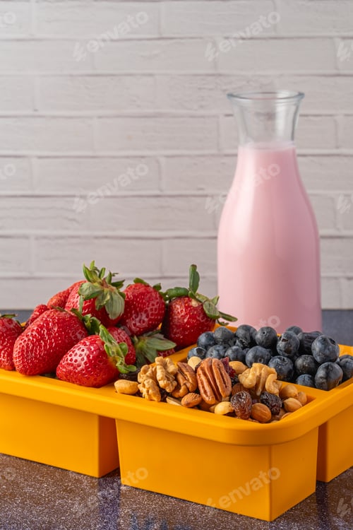 Preview: Lunchbox with fruits and granola and a glass of yogurt