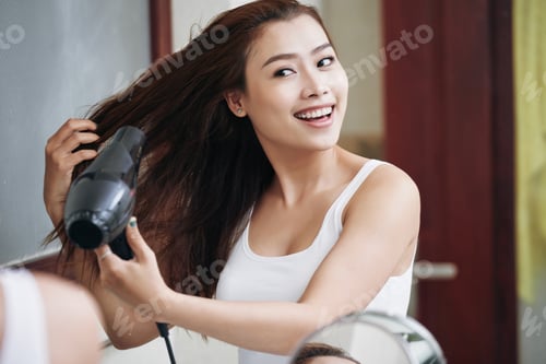 Preview: Happy ethnic woman drying hair in bathroom