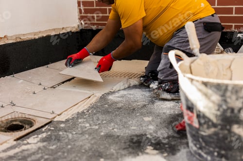 Preview: Midsection of a Hispanic man laying tile floor in a new house.