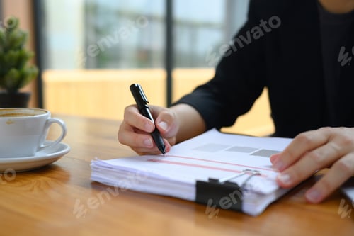 Preview: Cropped shot accountant in black suit working with financial reports on wooden desk