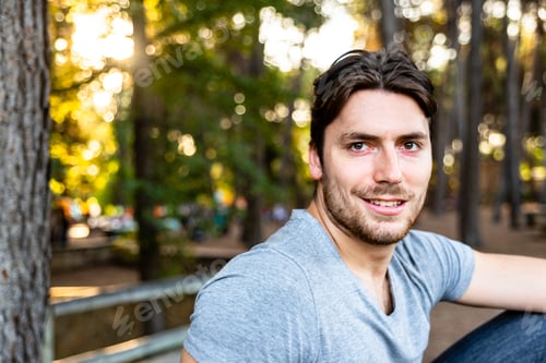 Preview: Close-up of a handsome young man model looks straight in front of the camera on a sunset