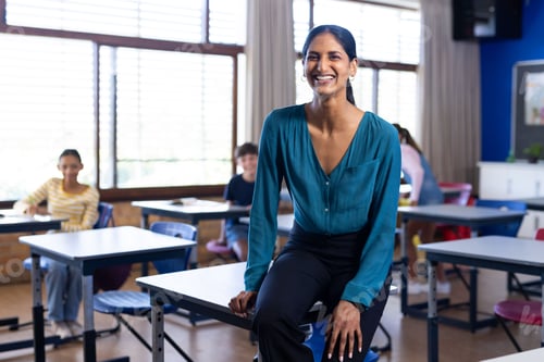 Visualização: Professora indiana sorridente sentada na mesa na sala de aula com os alunos na escola