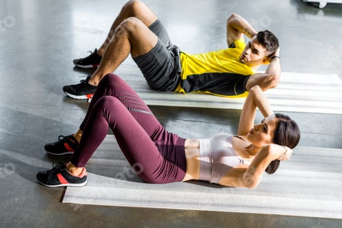 Preview: sportsman and sportswoman doing crunches on fitness mats in sports center