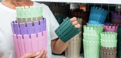 Preview: Senior woman looking and choosing some colored vases for flowers