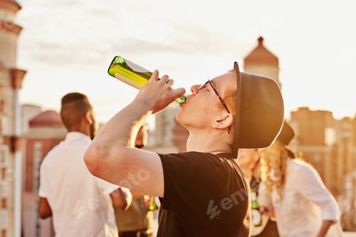 Preview: Young Ginger Man Drinking Beer on Rooftop
