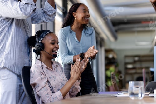 Preview: African American woman in headset clapping at office meeting, feeling excited