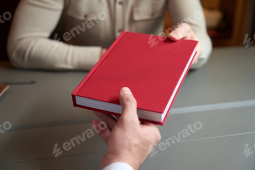 Preview: Man gives a red book to a colleague