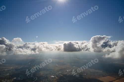 Preview: Aerial view from airplane window at high altitude of distant city covered