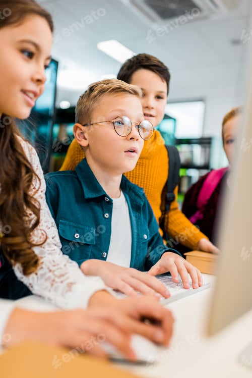 Preview: cropped shot of schoolchildren using desktop computer together in library
