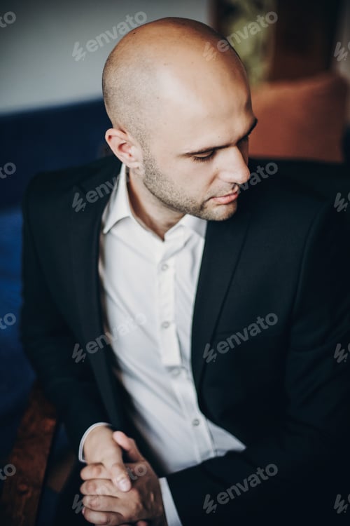 Preview: Stylish groom in black suit getting ready in the morning