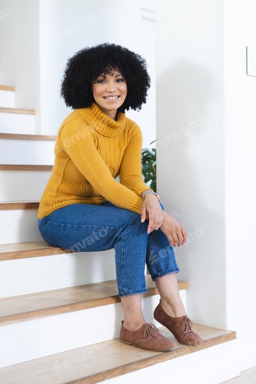 Preview: Happy african american woman sitting on stairs at home, copy space