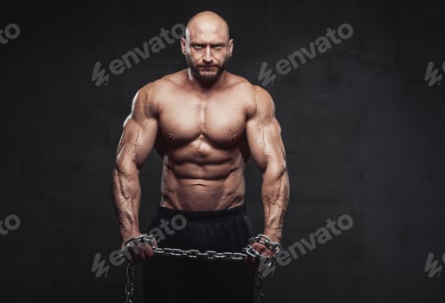 Preview: Powerful man with steel chains posing in dark background