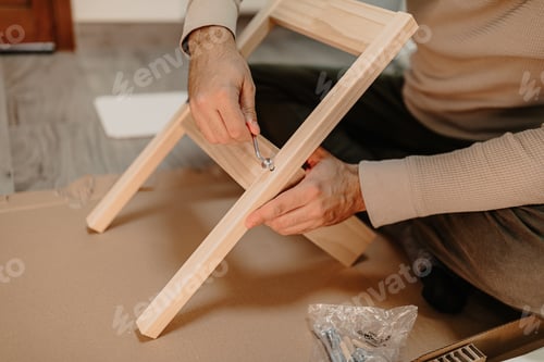 Preview: Skilled man assembles wooden furniture with a hex key