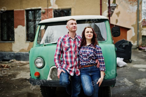Preview: Stylish couple wear on checkered shirt in love together against old minivan.